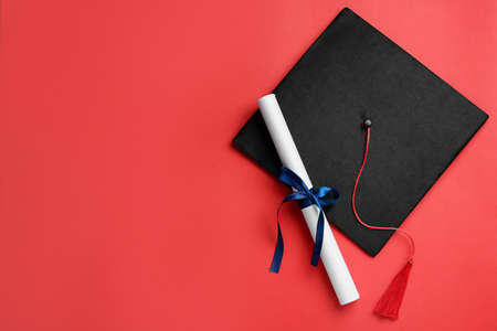 Graduation hat and diploma on red background, flat lay. Space for textの写真素材
