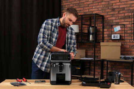 Man fixing coffee machine at table indoorsの写真素材