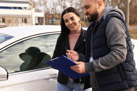 Young woman with instructor near car at driving school test trackの写真素材