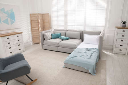 Stylish room interior with sleeper sofa and rocking chair. Additional place for guest