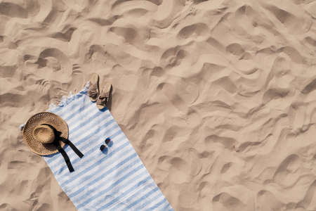Towel with beach accessories on sand, top view. Space for textの写真素材