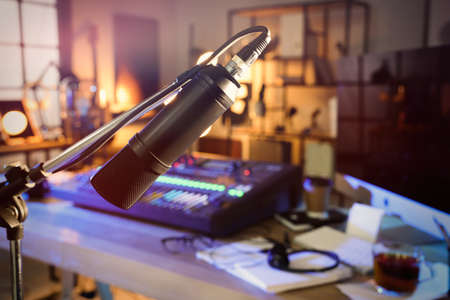 Microphone near table with professional mixing console in radio studio
