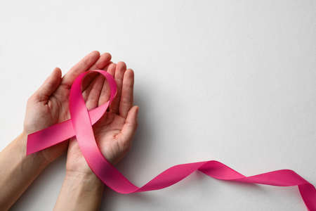 Woman holding pink ribbon on white background, top view with space for text. Breast cancer awareness conceptの写真素材