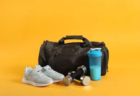 Sports bag and gym equipment on yellow backgroundの写真素材
