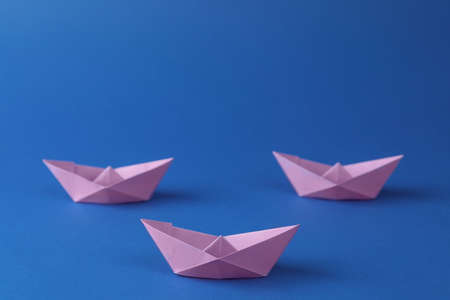 Handmade violet paper boats on blue background. Origami artの写真素材