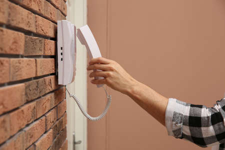 Man answering intercom call at home, closeupの写真素材