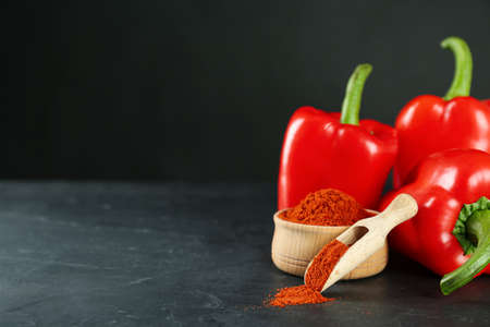Paprika powder and fresh bell peppers on black table. Space for textの写真素材