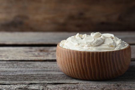 Bowl of tasty cream cheese on wooden table, space for textの写真素材