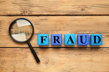 Word Fraud of cubes with letters and magnifying glass on wooden background, flat layの写真素材