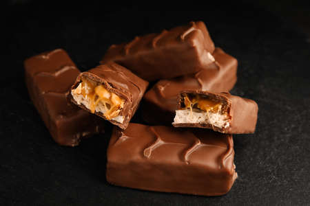 Chocolate bars with caramel, nuts and nougat on black table, closeupの写真素材