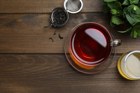 Cup of hot aromatic tea with mint and honey on wooden table, flat lay. Space for textの写真素材