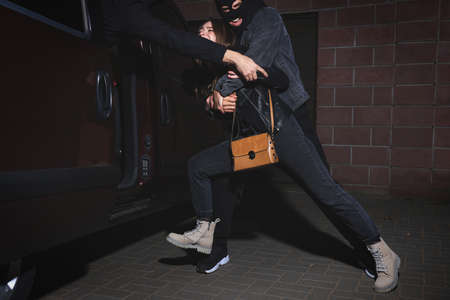 Criminals kidnapping young woman at night. Self defense conceptの写真素材