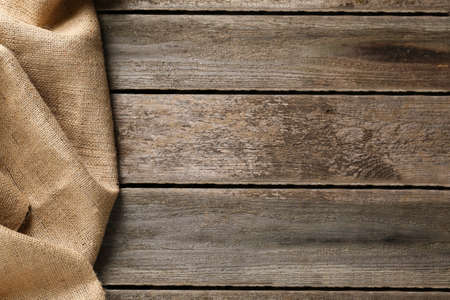 Natural burlap fabric on wooden table, top view. Space for text