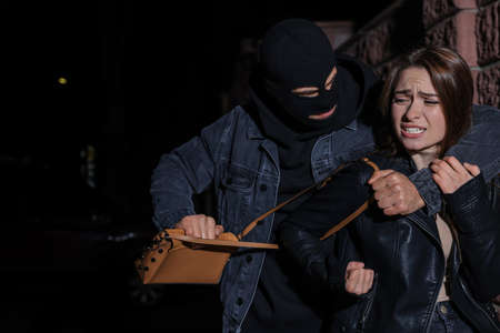 Woman fighting with thief while he trying to steal her bag outdoors at night. Self defense conceptの写真素材