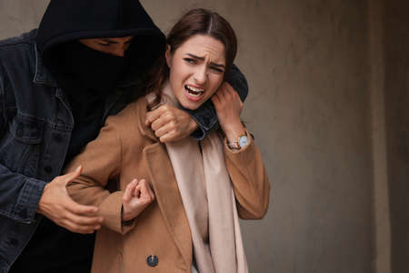 Woman defending herself from attacker near beige wall outdoorsの写真素材