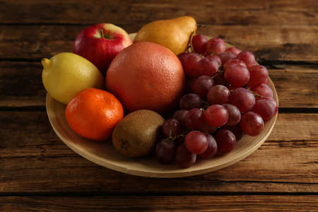 Fresh ripe fruits in bowl on wooden table, closeupの写真素材