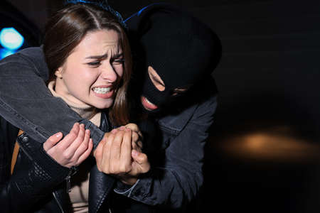 Woman defending herself from attacker outdoors at nightの写真素材