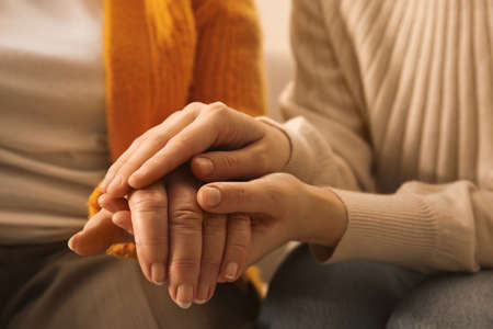 Young and elderly women holding hands together, closeupの写真素材