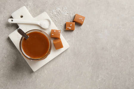 Tasty salted caramel and candies on light gray table, flat lay. Space for textの写真素材