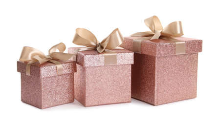 Shiny gift boxes with golden bows on white background