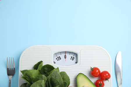 Scales, healthy food and cutlery on light blue background, flat lay. Space for textの写真素材