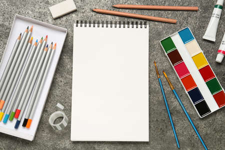 Flat lay composition with blank sketchbook on gray stone table. Space for text