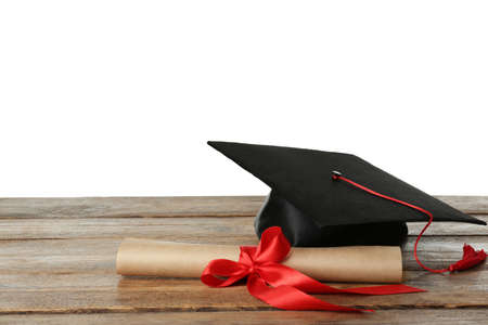 Graduation hat and diploma on wooden table against white background, space for textの写真素材