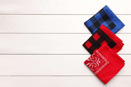 Folded bandanas with different patterns on white wooden table, flat lay. Space for textの写真素材