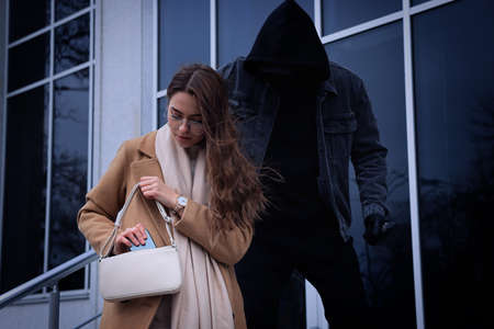 Criminal with knife attacking young woman near building. Self defense conceptの写真素材