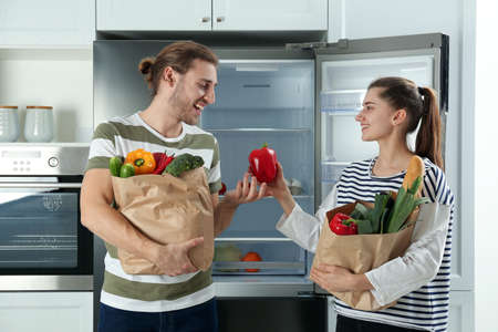 Couple with fresh products near refrigerator in kitchenの写真素材