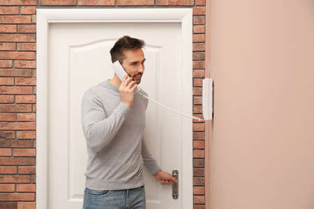 Man with handset answering intercom call indoors