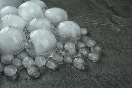 Many melting ice balls on dark gray table, closeup. Space for text