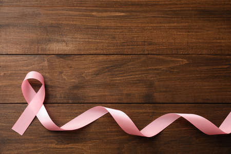 Pink ribbon on wooden table, top view with space for text. Breast cancer awareness conceptの写真素材