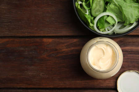 Jar of delicious mayonnaise and fresh salad on wooden table, flat lay. Space for textの写真素材