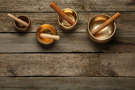Golden singing bowls and mallets on wooden table, flat lay. Space for textの写真素材