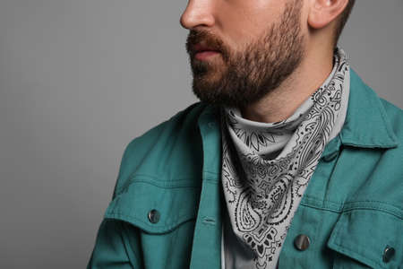 Fashionable young man in stylish outfit with bandana on gray background, closeupの写真素材