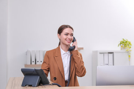 Female receptionist talking on phone at workplaceの写真素材