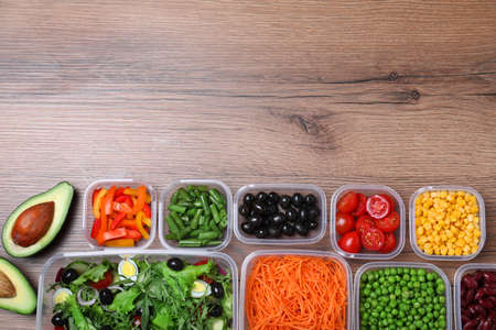 Set of plastic containers with fresh food on wooden table, flat lay. Space for text