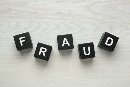 Black cubes with word Fraud on white wooden table, flat layの写真素材