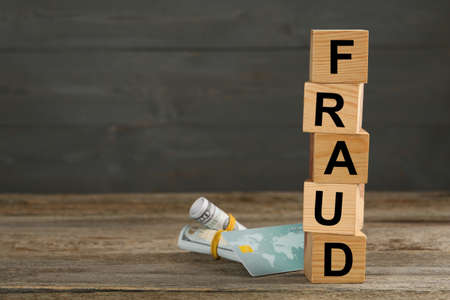 Cubes with word Fraud, credit card and money on wooden table, space for textの写真素材