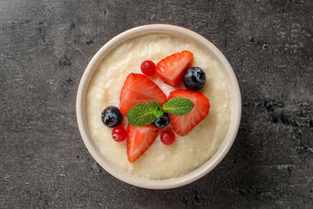 Delicious semolina pudding with berries and mint on gray table, top view