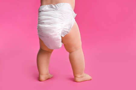 Back view of cute baby in dry soft diaper standing on pink background, closeupの写真素材