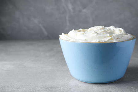 Bowl of tasty cream cheese on light gray table, space for textの写真素材