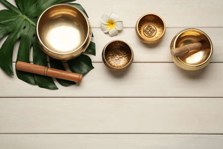 Flat lay composition with golden singing bowls on white wooden table. Space for textの写真素材