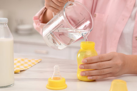 Woman preparing infant formula at table indoors, closeup. Baby milkの写真素材