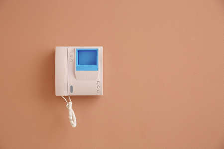 Modern intercom system with handset on beige wall, space for text