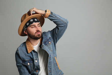 Fashionable young man in stylish outfit with bandana on gray background, space for text