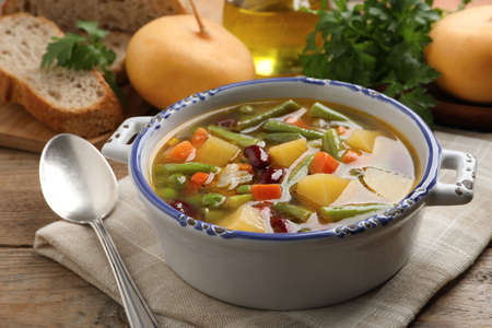 Bowl of tasty turnip soup with napkin and spoon on wooden tableの写真素材