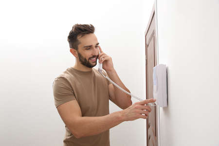Man with handset answering intercom call indoors