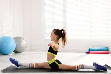 Cute little girl doing gymnastic exercise indoors. Front splitの写真素材